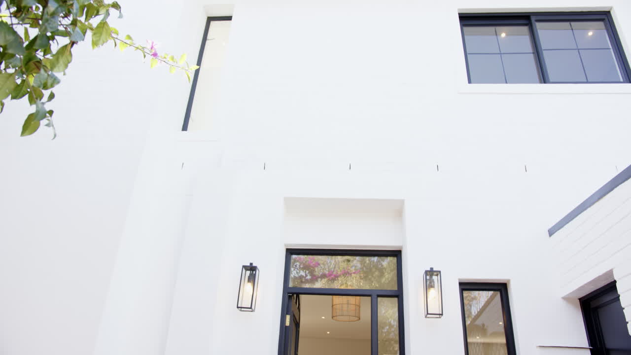 Modern house exterior with large windows and open front door, inviting entrance