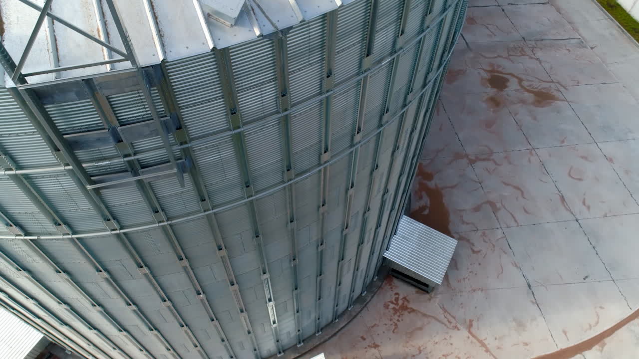 Large grain elevator. Industrial equipment for agricultural crop. Modern silver hangar. Metal bin for storing grains. Close-up.