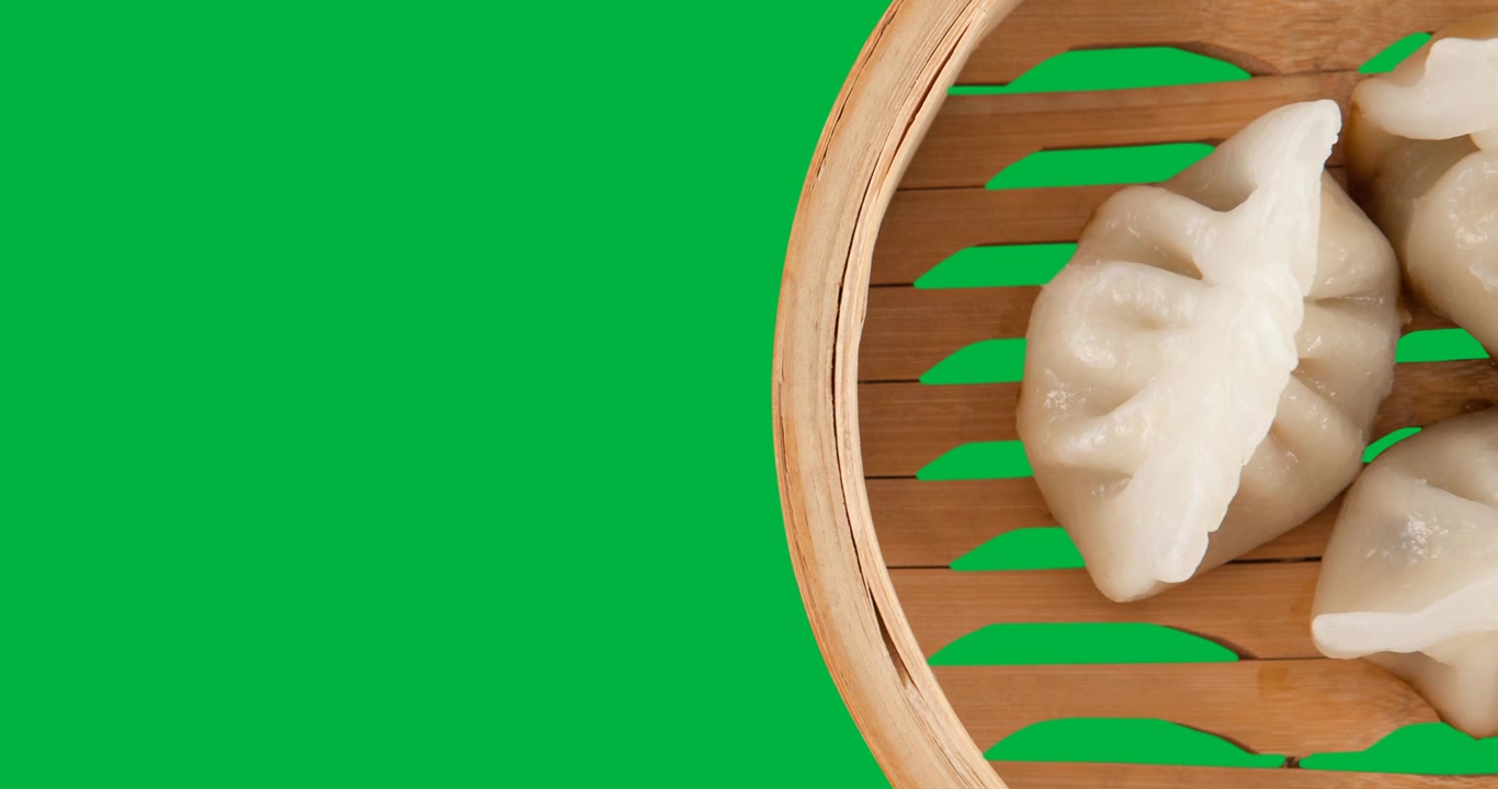 Close up view of dumplings in a basket against black background