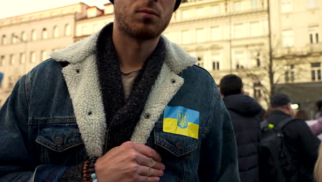 Protester-with-Ukraine-flag-on-chest-at-a-demonstration,-Prague,-slow