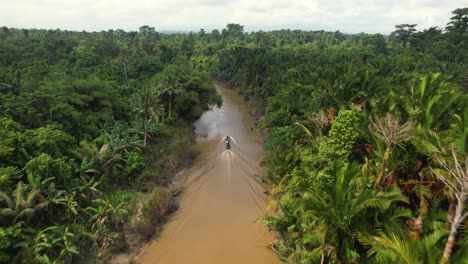 una vista aérea de un dron 4k de un barco de cola larga navegando por un río en la jungla