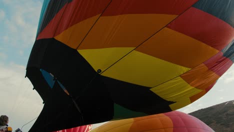 Side-profile-of-flames-inflating-filling-up-colorful-hot-air-balloon-at-sunrise-in-the-cold-winter-morning