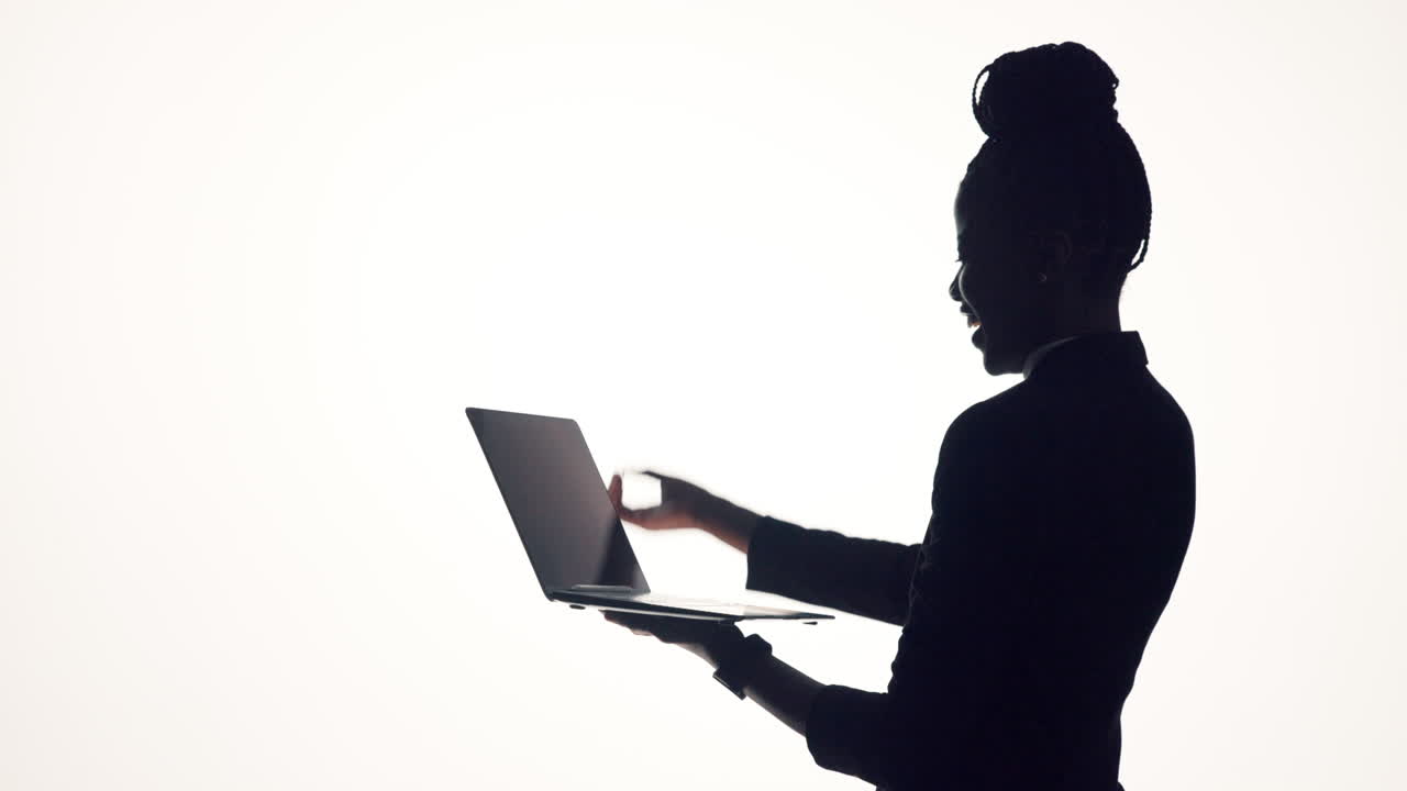 Silhouette of a successful businesswoman celebrating with a laptop