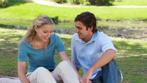 A-woman-sitting-as-her-boyfriend-sits-beside-her-as-they-kiss-and-then-look-at-the-camera