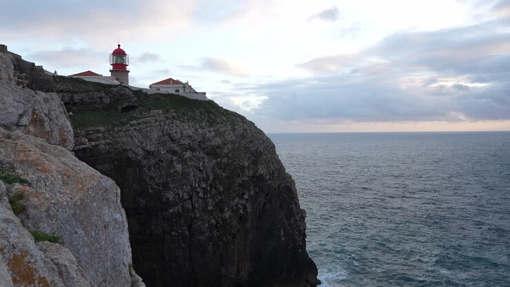 Ripresa aerea di un faro costruito su una scogliera lungo la costa atlantica, sotto un cielo magnifico.