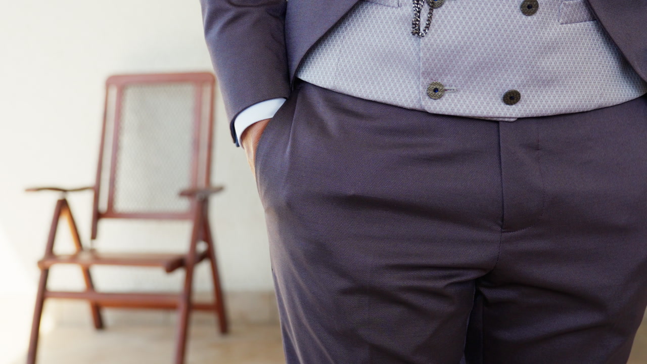 Close-up of groom placing hands in pockets while standing ready for ceremony.