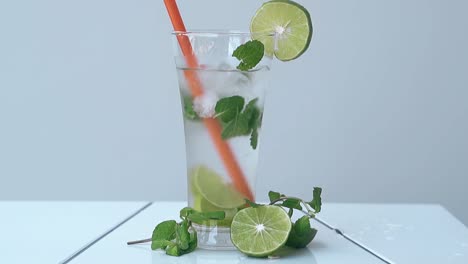 glass with orange straw inside stands on white table