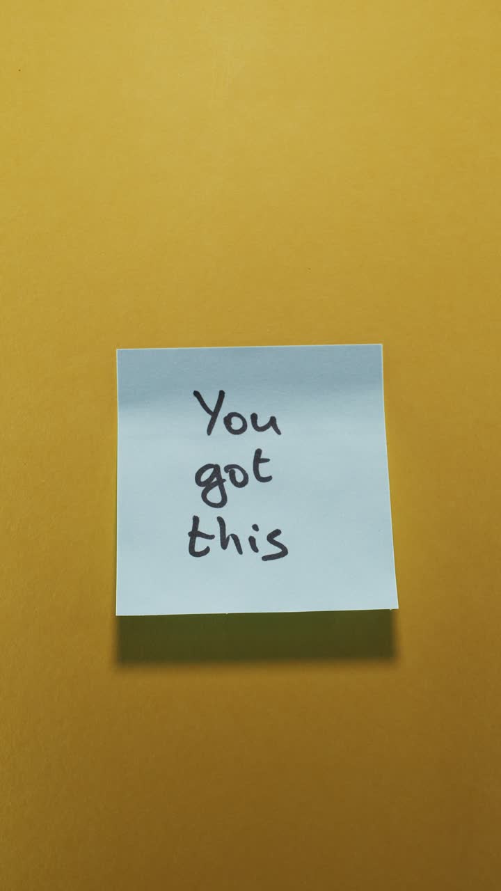Portrait shot of a light blue sticky note reading "You Got This" on a yellow background