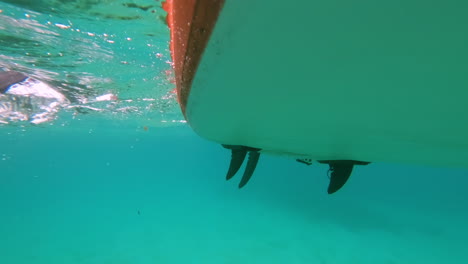 detalle de primer plano bajo el agua de sup paddle boarding en el océano azul claro