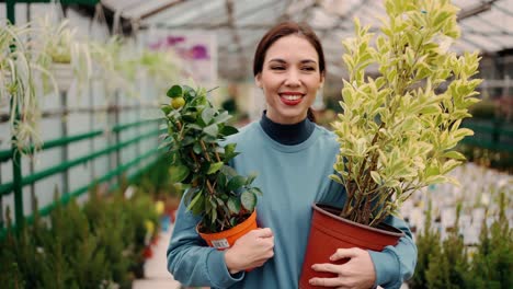 A-La-Mujer-Le-Gusta-Comprar-Plantas-En-El-Mercado,-Le-Encantan-Las-Plantas-Vivas,-Caminar-Con-Dos-Macetas