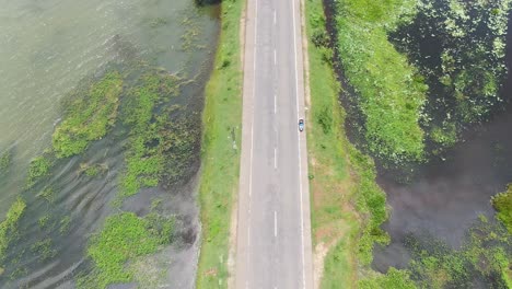 tuktuk conduciendo en una carretera que está rodeada por agua por ambos lados