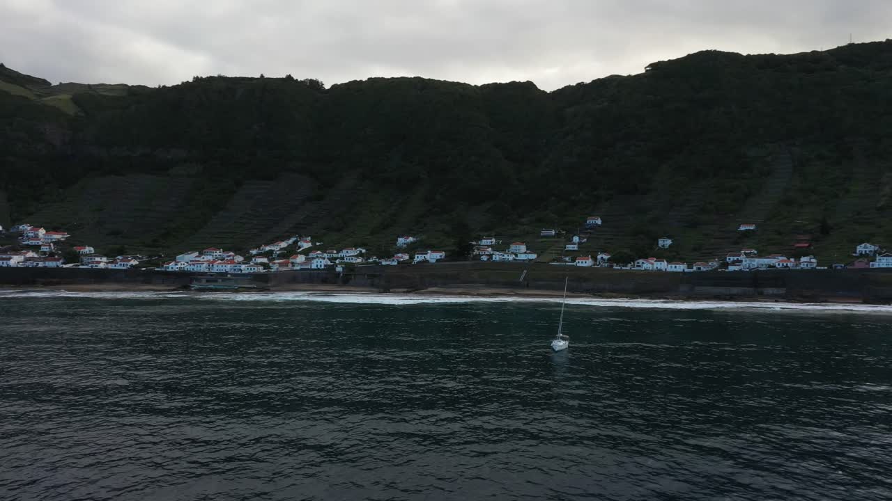 Sailboat near a coastal village in a serene landscape