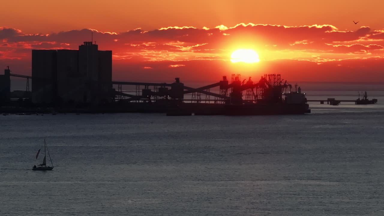 Lissabons silhuett vid solnedgången över Tejo-floden med en segelbåt och strålande sol
