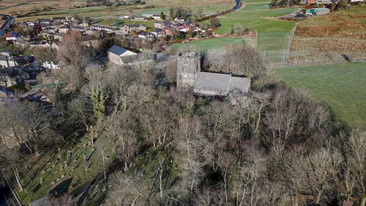 Aerial footage of the village of Denshaw, and the old church and graveyard, a typical rural village in the heart of the Pennines