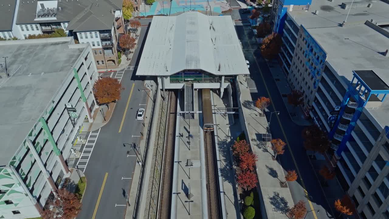 Buckhead, Atlanta, Georgia, United States of America - A Raised Station Platform Sits Between Rail Tracks, Surrounded by Buildings and Tree-lined Streets - Drone Flying Forward
