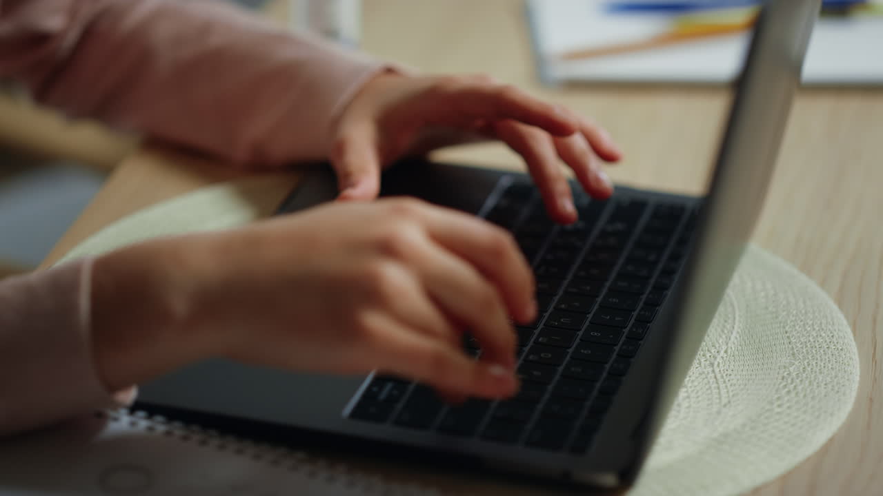 Girl hands typing computer keyboard indoors. Kid using laptop for schooling.