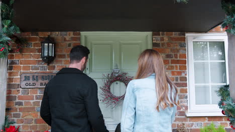 family being greeted by grandparents as they arrive for visit on christmas day with gifts