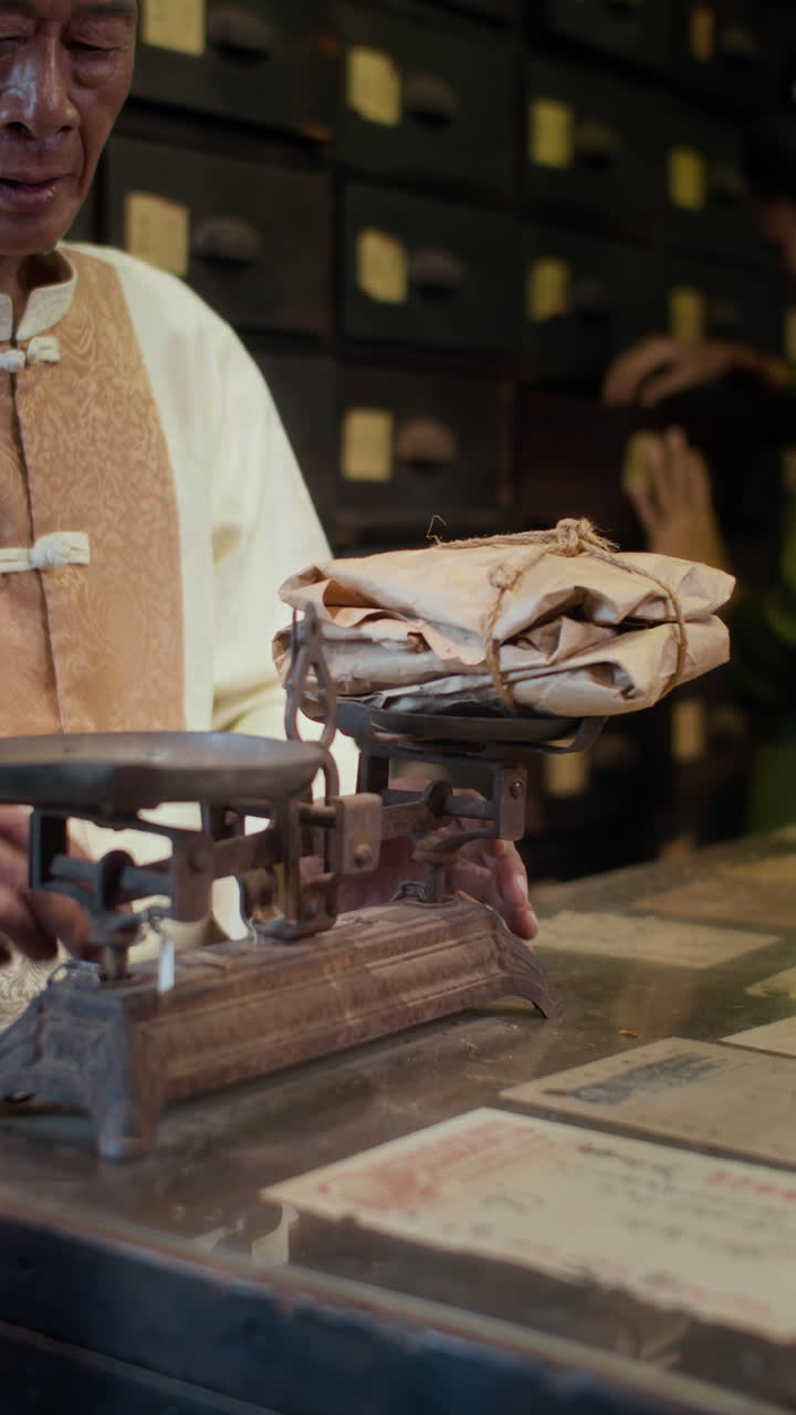 Elderly Alternative Medicine Pharmacy Worker Weighing Dried Ingredients on Scales