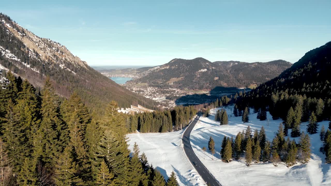 impresionante vista aérea desde un avión no tripulado: paso de montaña cubierto de nieve, vista panorámica del schliersee en alemania, paisaje de los alpes bávaros con carretera y lago de montaña lejano en la temporada de invierno