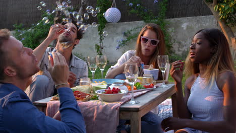 friends blowing bubbles during picnic in garden