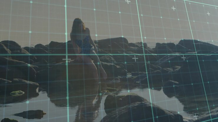 Digital grid overlay emerging spurring woman wearing blue swimsuit pushing and stepping into water