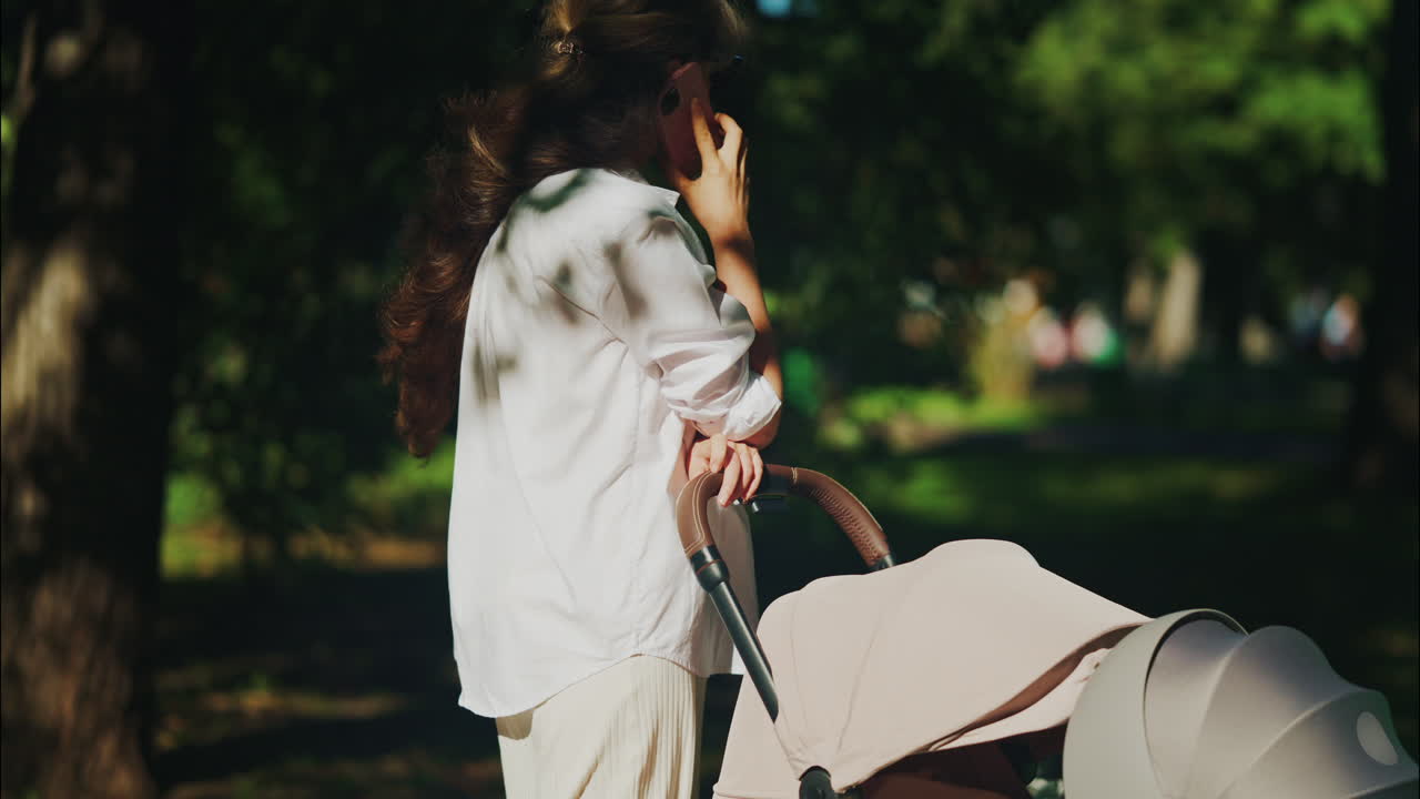 Young mother sitting on a park bench next to a stroller, enjoying a peaceful outdoor moment with her baby