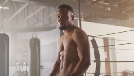 video eines fitten afroamerikanischen mannes, der sich auf ein boxtraining im fitnessstudio vorbereitet