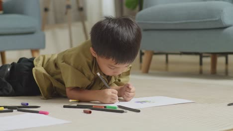 close up of asian kid lying on the floor drawing at home