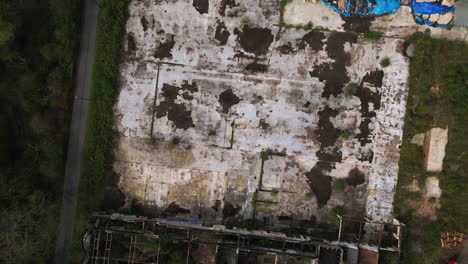 derelict concrete foundation near abandoned industrial building, aerial top down view