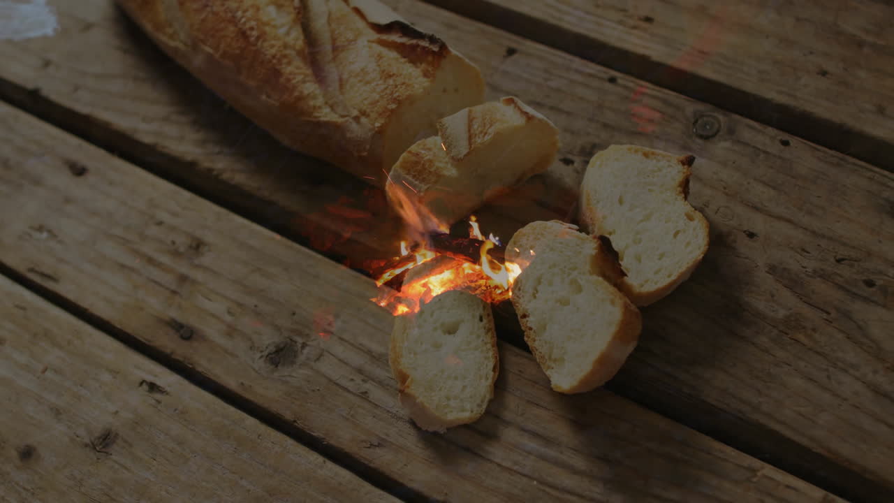 Animation of fire overlay under sliced bread on wooden surface