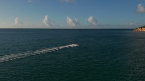 Birds-eye-view-tracking-woman-tourist-jet-skier-ride-on-deep-blue-tropical-water-with-horizon-background