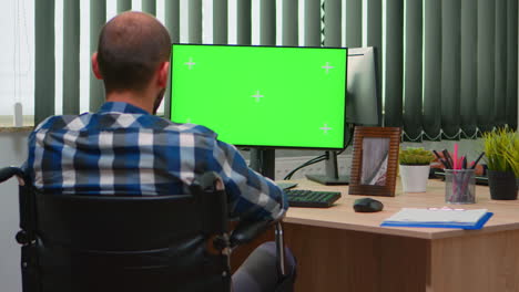 disabled freelancer looking at pc with green screen