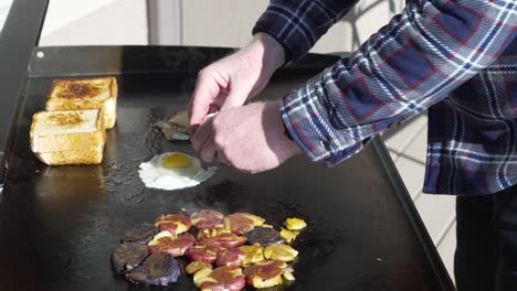 agrietar y freír huevos en la plancha superior plana para un sándwich de desayuno en tostadas de texas - cierre aislado en cámara lenta