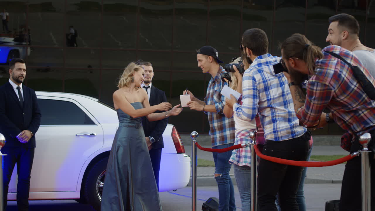 Celebrity interacting with paparazzi and fans on a red carpet