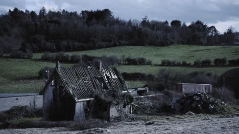 a damaged shelter in the middle of the greenfield and forest in northern ireland. -wide shot