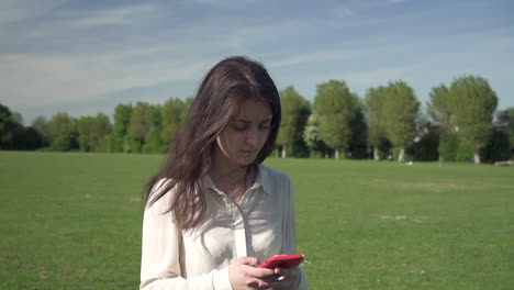 Feliz-Sonriente-Hermosa-Chica-Italiana-Disfrutando-De-Caminar-Por-El-Parque-Mientras-Escribe-Texto-A-Través-De-Un-Teléfono-Inteligente,-Una-Turista-Positiva-Que-Usa-Tecnología-Para-Comunicarse