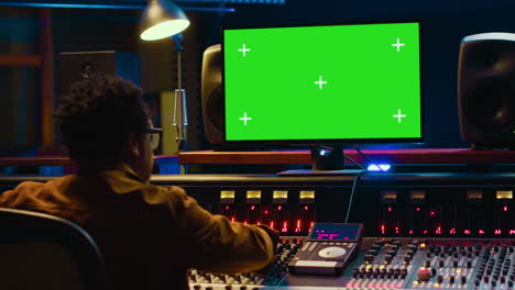 técnico de audio trabaja en la postproducción de música con pantalla verde en la sala de control