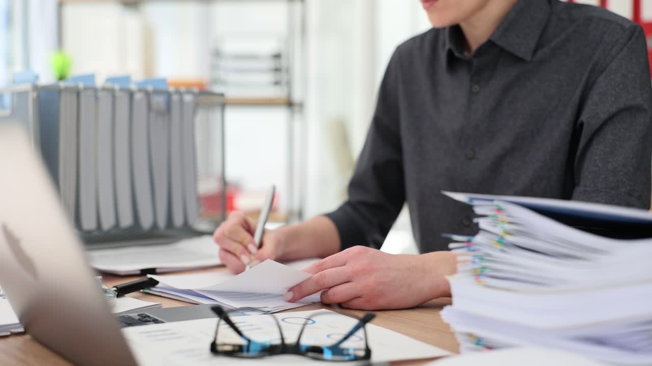 Person working at an office desk with documents and laptop