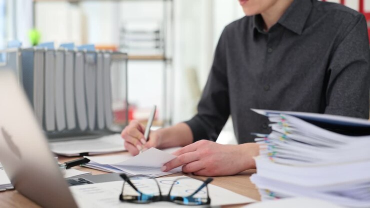 Person working at an office desk with documents and laptop
