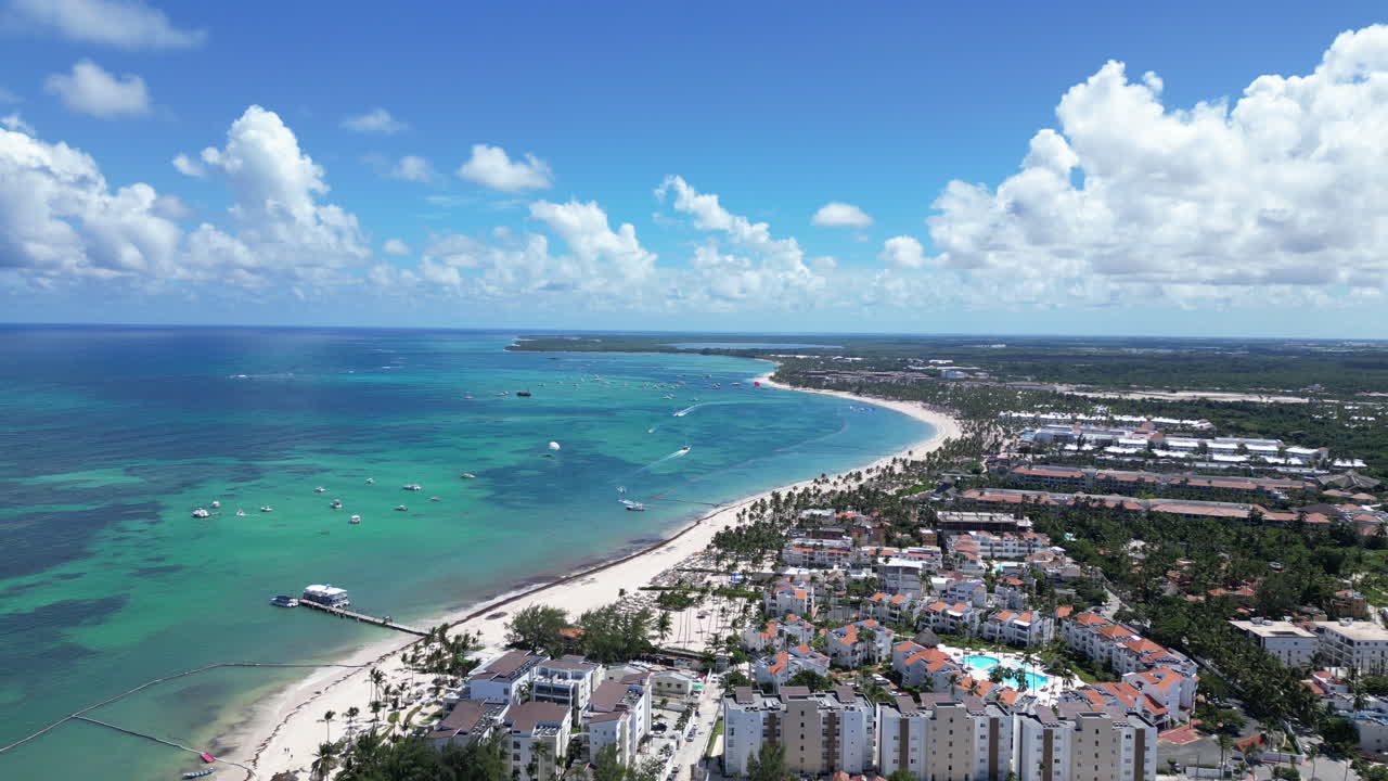 Tomada de drone de uma costa de areia branca com mar cristalino e resorts.