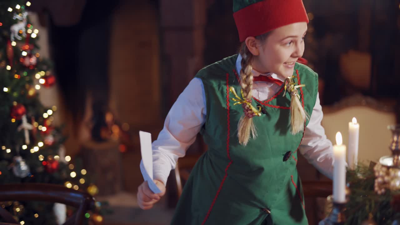 Curious elf looking at envelopes in the decorated room. Candles glowing on the table and a tricky elf holding letters and talking to someone. Christmas time.