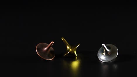 three tops spinning on a dark surface