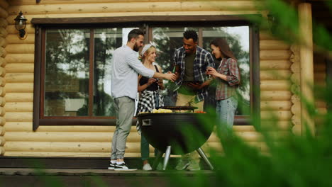 multiracial people near bbq grill outside. guys clinking glasses on party