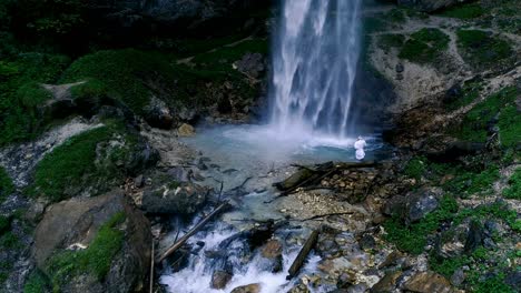 man with beard is doing waterfall-meditation under big waterfall