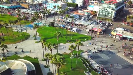 drone volador sobre un día soleado en venice beach california palmeras, parque de patinaje, bicicletas, ciudad y gente