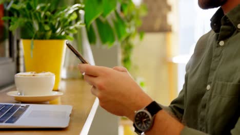 Close-up-of-man-using-mobile-phone-at-table-4k