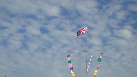 pride rainbow flags and england flag at the top with partly cloudy sky at the backround slow motion