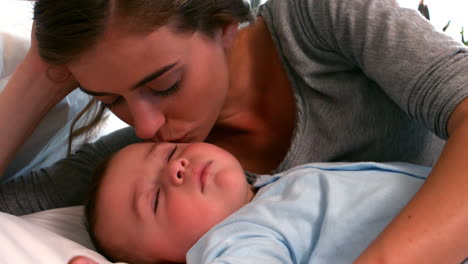 Mother-lying-with-sleeping-baby-boy-on-bed