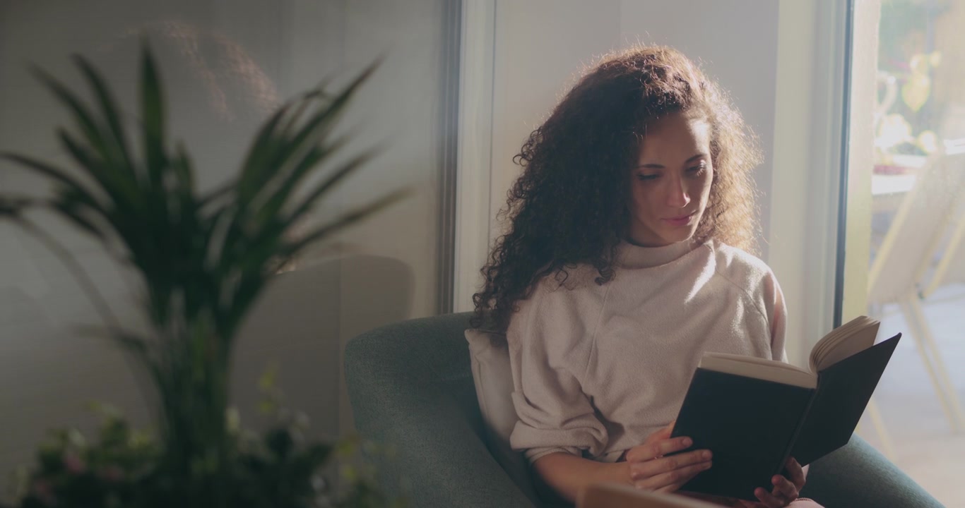 Woman reading a book next to a window