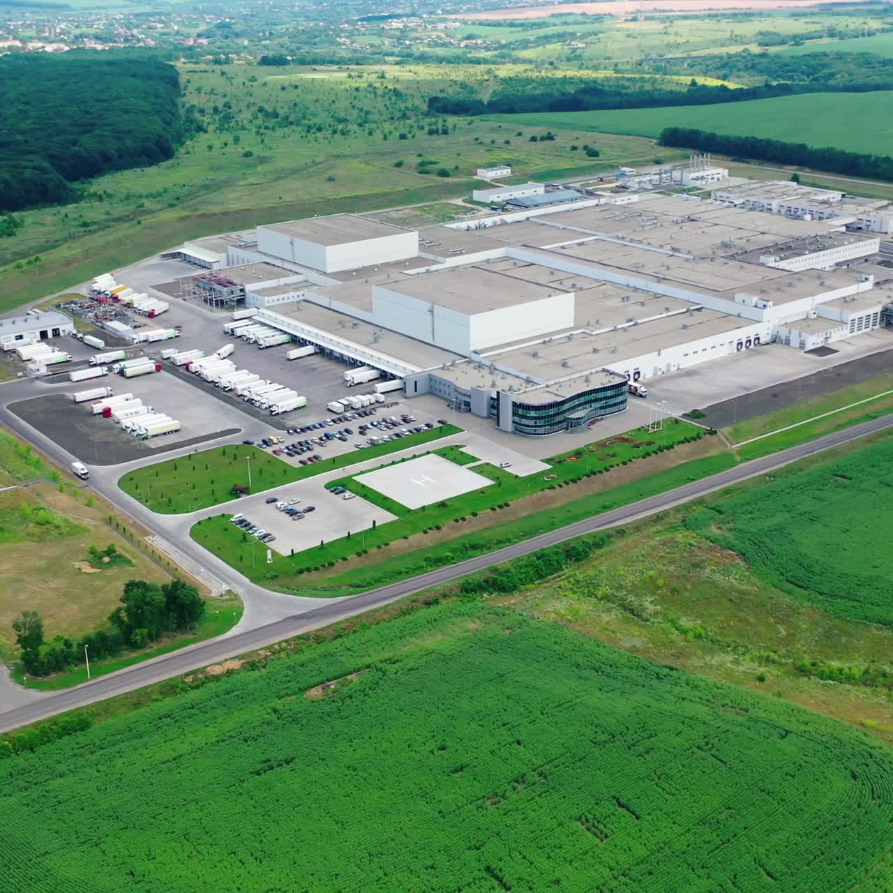 Harmful factory in natural environment. Huge industrial plant surrounded by beautiful green nature. Aerial view. Motion back
